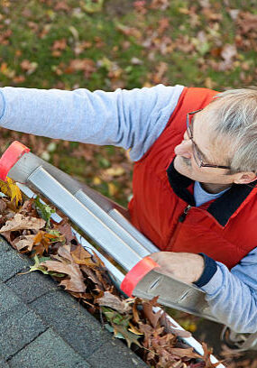 Senior man cleaning leafs out of gutter.More of this model.