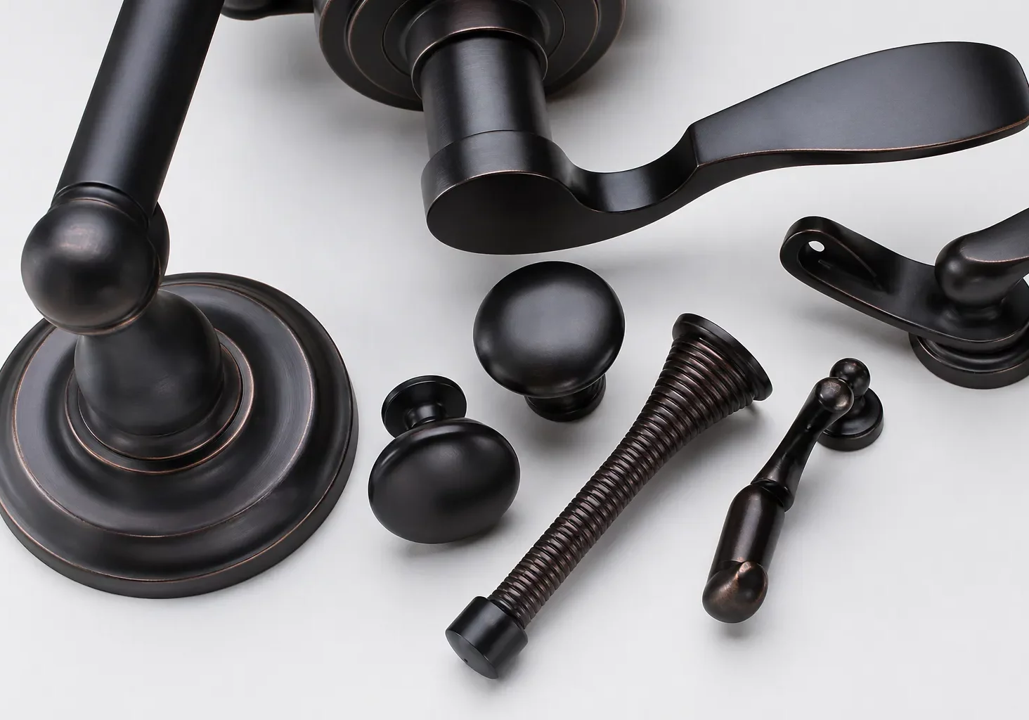 Oil-rubbed bronze door levers and knobs hardware set with modern handles and cabinet pulls on white background